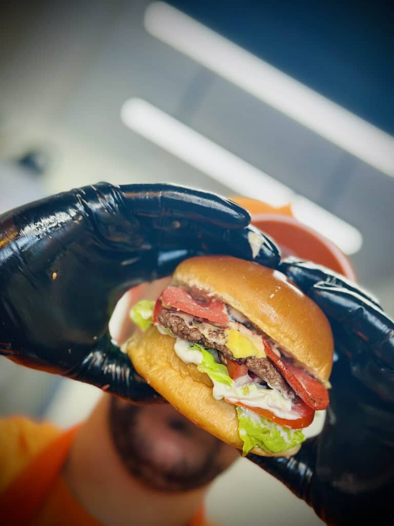 Burger tenu à la main, prêt à servir